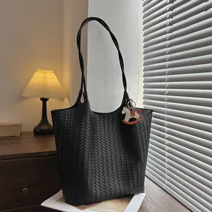 Dettaglio ravvicinato di una borsa tote intrecciata nera con un ciondolo a forma di cavallo