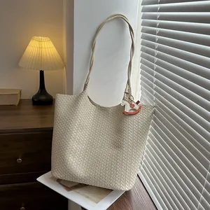 Vista dettagliata della borsa tote intrecciata crema con ciondolo cavallo a dondolo