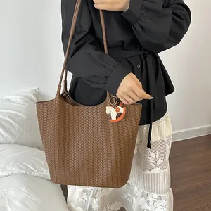 Vista dettagliata della grande borsa tote intrecciata marrone con ciondolo a cavallo