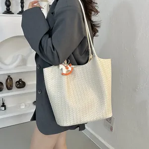 Dettaglio borsa tote intrecciata bianca con ciondolo a forma di cavallo arancione