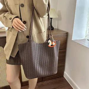 Scatto dettagliato della borsa tote intrecciata marrone scuro con un grazioso ciondolo a cavallo
