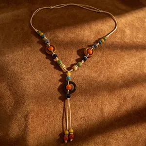 Boho κολιέ με κεραμικές χάντρες σε καφέ σουέτ φόντο με καλλιτεχνικές σκιές και φως