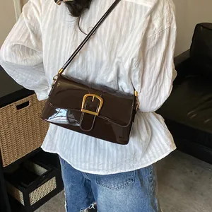 Stylish retro dark brown patent leather baguette shoulder bag with elegant gold buckle on model