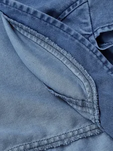 Primo piano della trama del tessuto denim blu e delle rifiniture a doppia cucitura