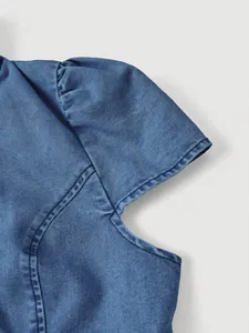 Primo piano dettagliato del design delle maniche a sbuffo su una giacca di jeans blu.