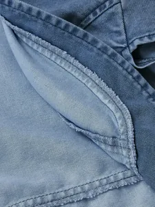 Vista dettagliata della giacca di jeans blu con cuciture e trama del tessuto denim