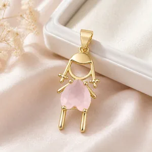Primer plano de un colgante de niña en tono dorado con una circonita rosa en forma de corazón