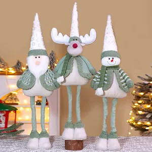 Drei salbeigrüne und weiße Weihnachts-Plüschfiguren auf einem festlichen Tisch