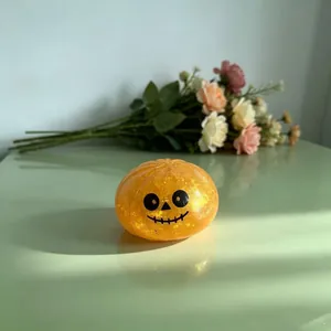 Juguete antiestrés de calabaza de Halloween naranja con purpurina y cara sonriente.