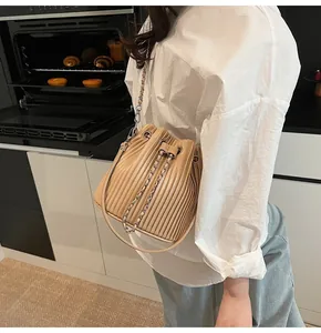 Detail shot of a pleated beige bucket bag with chain strap styled in a kitchen setting