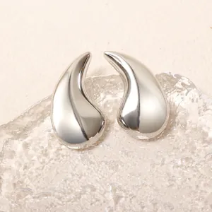 Gros plan détaillé de boucles d'oreilles gouttes d'eau argentées sur verre texturé