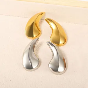 Détail rapproché de boucles d'oreilles gouttes minimalistes en or et argent poli