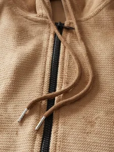 Detailed macro shot of textured pineapple grid fabric and zipper on a men's hoodie