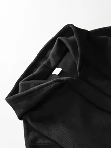 Close-up detail of black waffle knit fabric and collar of men's hooded zip-up jacket.