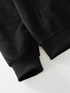 Detail view of black pineapple grid jacket showing ribbed cuff and fabric texture