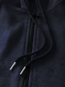 Macro view of navy blue waffle knit hoodie with metal drawstring tips and zipper
