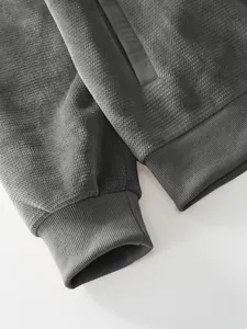 Close-up detail of gray men's jacket showing pineapple grid fabric and ribbed cuff.