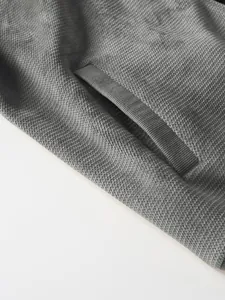 Close-up detail of gray pineapple grid knitted cardigan showing ribbed pocket texture.