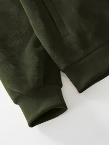 Detailed macro shot showing olive green pineapple grid texture and ribbed cuff of men's jacket