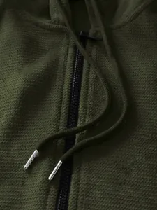 Close-up of olive green pineapple grid texture and metal drawstring tips on hoodie
