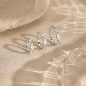 Detailansicht von drei Creolen aus Sterlingsilber mit Marquise-Kristallen auf Sand