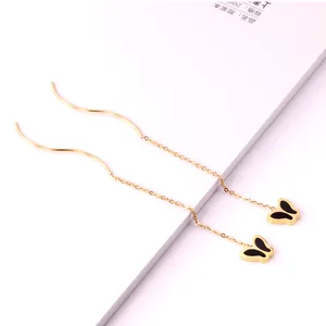Close-up of elegant gold tassel threader earrings with black enamel butterfly pendants