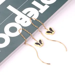 Detailed view of long gold chain threader earrings with black butterfly pendants