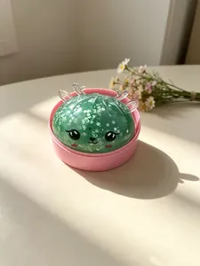 Nahaufnahme eines glitzernden grünen Rentier-Squishy-Spielzeugs in einer rosa Basis