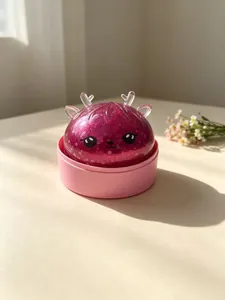 Makroaufnahme eines lila Rentier-Quetschspielzeugs mit Glitzer in einem rosa Behälterboden