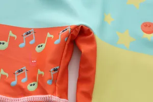 Macro view showing cute cartoon musical notes and stars on colorful swimsuit fabric.