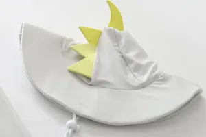 Close-up detail view of a grey children's swim hat featuring cute yellow dinosaur spikes