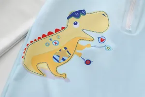 Close-up of cute yellow cartoon dinosaur print on light blue boys one-piece swimwear