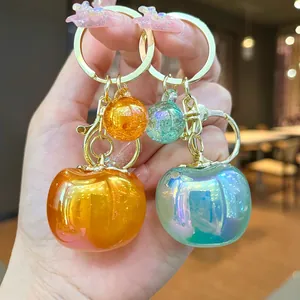 Close-up of cute iridescent persimmon keychains in orange and teal as bag pendants.