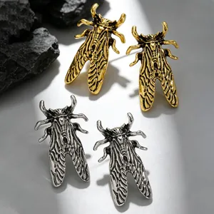 Detailed macro view showing vintage cicada-shaped stud earrings in gold and silver finishes