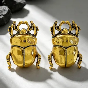 Detailed macro shot of vintage gold-finished scarab beetle rings on stone surface.