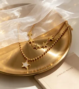Macro detail showing a light luxury gold double-layer necklace with star charms on a tray