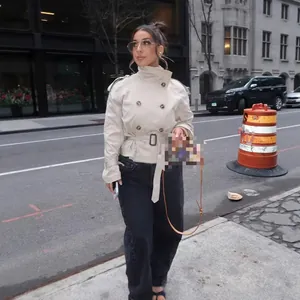 Elegante trench corto doppiopetto da donna indossato in un contesto di strada urbana