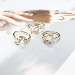 Gold letter rings with sparkling zircon accents and elegant cursive initials.