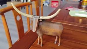 Detailed macro view of a resin longhorn bull statue featuring wood grain texture.