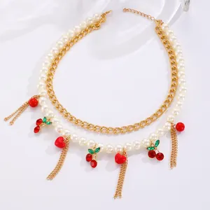 Detail of elegant double-layered pearl necklace with red cherry charms and gold chains