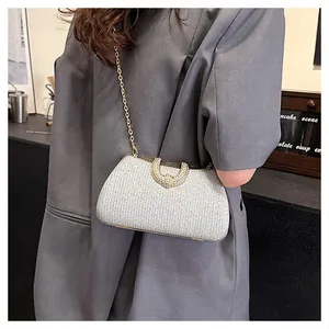 Detailansicht einer silbernen Glitzer-Abendtasche mit goldener Kette an einem Model.