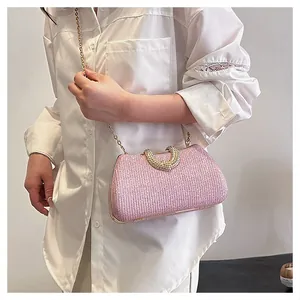 Rosa glitzernde Abendtasche mit goldener Kette, getragen von einem Modell