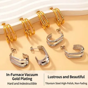Close-up detail of geometric titanium steel hoop earrings in polished gold and silver finishes.