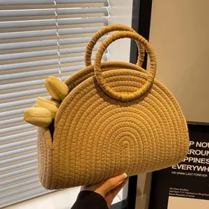 Detail van een handgeweven strooien tas met elegante ronde handvatten en tulpen