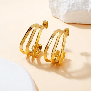 Detail view of gold-plated triple-row geometric titanium steel earrings on stone.