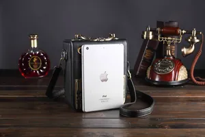 Einzigartige schwarze Vintage-Handtasche mit goldenem Griff neben iPad zum Größenvergleich