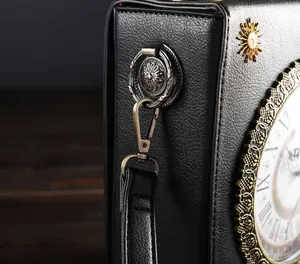 Detailansicht der antiken Bronzebeschläge und Sonnenanhänger an der schwarzen Retro-Uhrtasche