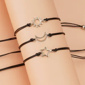 Detailansicht der silbernen Sonnen- Mond- und Sternanhänger an schwarzen Armbändern