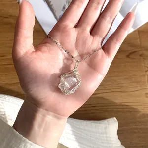 Close-up of handmade wire-wrapped clear quartz crystal pendant on silver chain