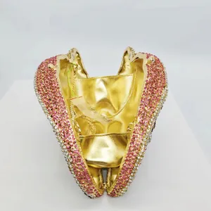 Detail view of the shell-shaped evening bag showing the golden interior and pink rhinestones.